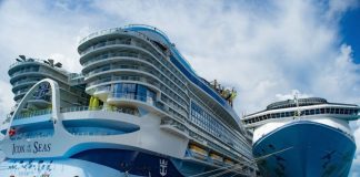A massive cruise ship towers over a dock in Cozumel, Mexico while passengers cue to board