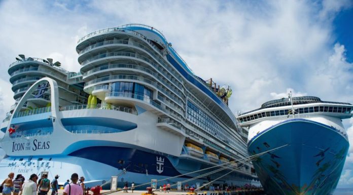 A massive cruise ship towers over a dock in Cozumel, Mexico while passengers cue to board