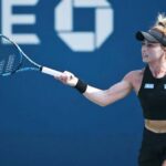 Mexican professional tennis player Renata Zarazua in a black tennis outfit and her blonde hair tired up in a bun, hitting a tennis ball with a forehand swing during a match.