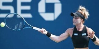 Mexican professional tennis player Renata Zarazua in a black tennis outfit and her blonde hair tired up in a bun, hitting a tennis ball with a forehand swing during a match.