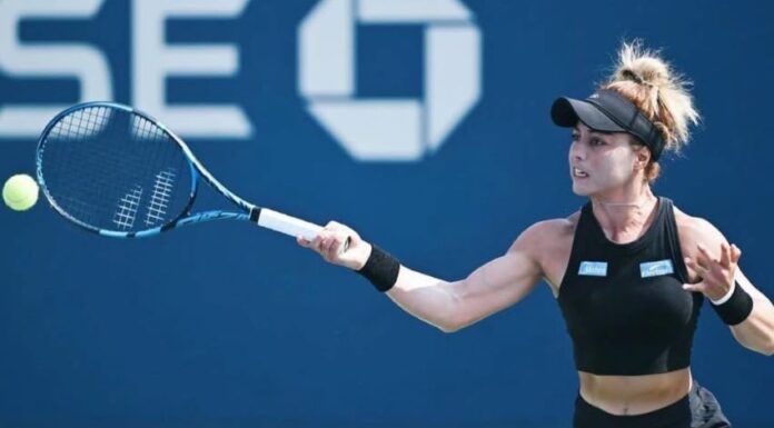 Mexican professional tennis player Renata Zarazua in a black tennis outfit and her blonde hair tired up in a bun, hitting a tennis ball with a forehand swing during a match.