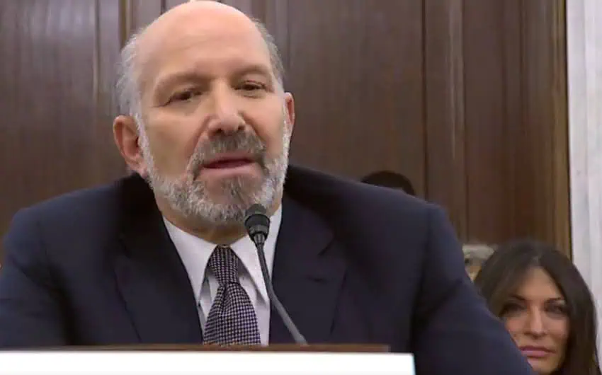 Howard Lutnick, a balding man in a suit, sitting at a table in front of a microphone as he testitfies in his confirmation hearing for Commerce Secretary before the U.S. Senate.