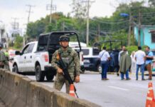 A Mexican soldier stands guard with a gun on a highway in Tabasco