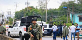 A Mexican soldier stands guard with a gun on a highway in Tabasco