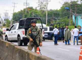 A Mexican soldier stands guard with a gun on a highway in Tabasco