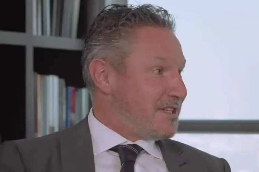 Closeup screenshot of Mark. R. Thomas, World Bank country director for Mexico, Colombia and Venezuela, speaking to an interviewer. A bookshelf filled with journals and books can be seen behind him.