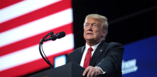 U.S. President Trump speaks at a podium in front of an American flag