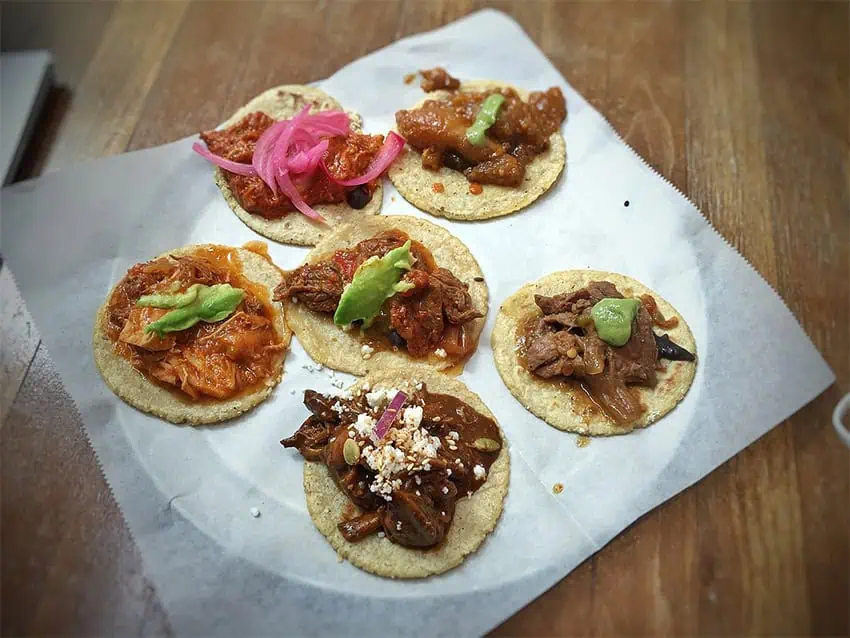 Six tacos de guisados with various stewed fillings