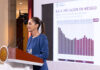 President Sheinbaum stands at a podium during her morning press conference (mañanera), in front of a graph related to low inflation