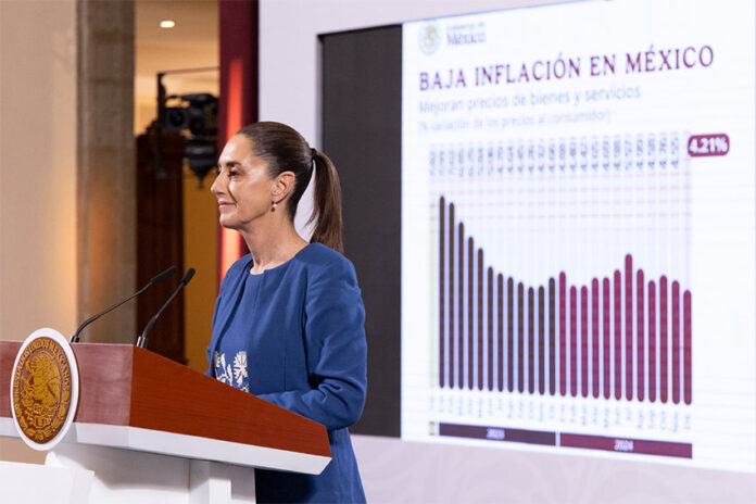 President Sheinbaum stands at a podium during her morning press conference (mañanera), in front of a graph related to low inflation