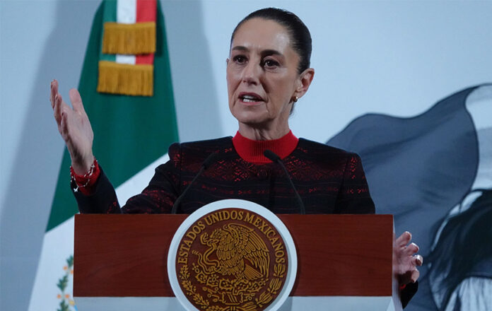 President Sheinbaum stands in front of a Mexican flag at her morning press conference