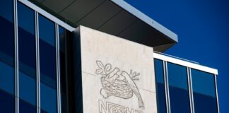 Glass skyscraper corporate headquarters of Nestle with Nestle name and logo stenciled onto onto a marble monolith on the building.