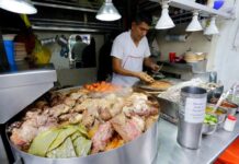 A Mexico City taquero prepares food in the background, with a pile of roasted nopales, meat and vegetables in the foreground