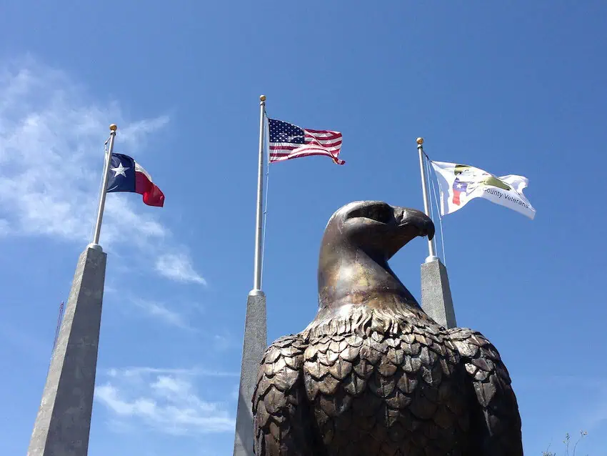 The flags of Texas State and the United States wave in the air.