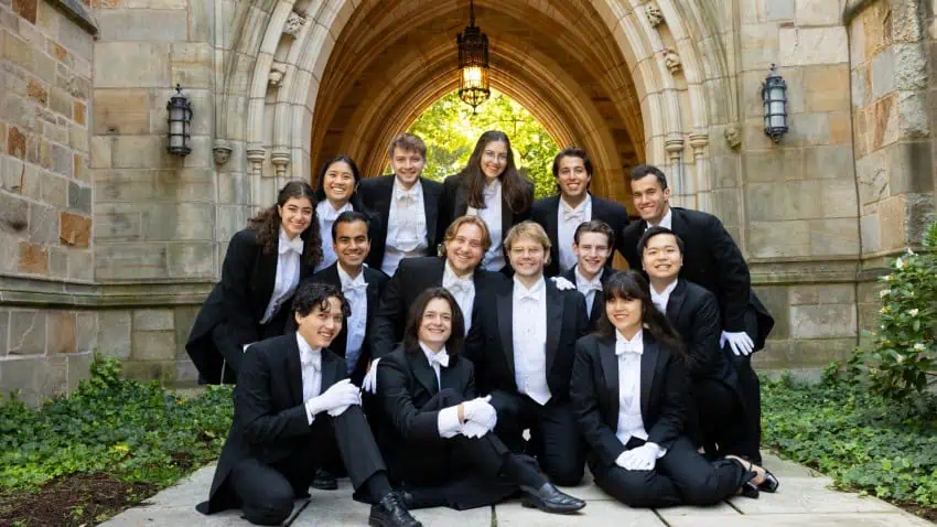 Members of Whiffenpoofs group pose in front of stone arch