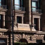 Facade of Bank of Mexico building in Mexico City, done in a classical style of architecture with arches, pillars, and balconies at each upper floor window