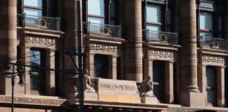 Facade of Bank of Mexico building in Mexico City, done in a classical style of architecture with arches, pillars, and balconies at each upper floor window