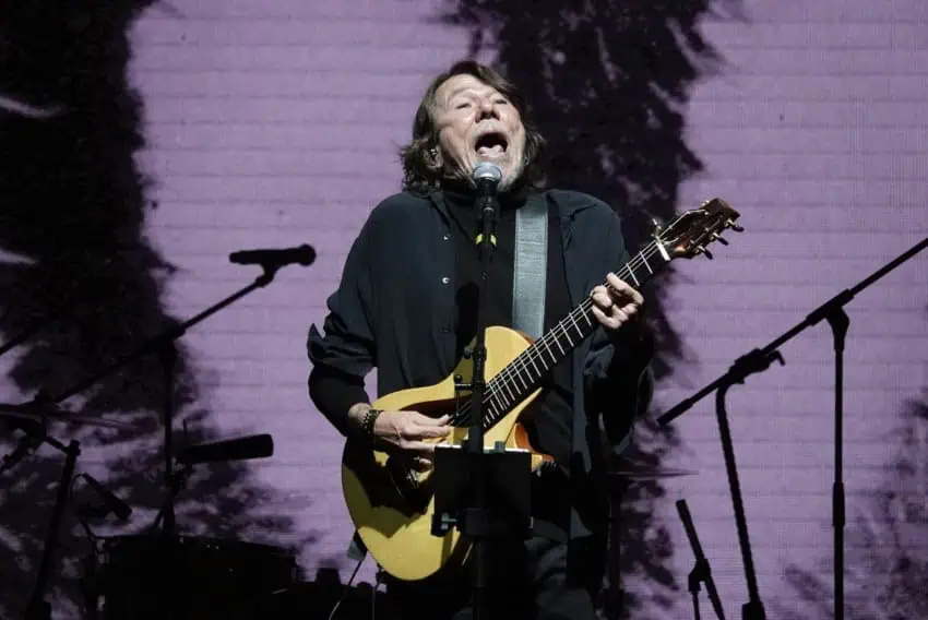 A middle-aged musician playing an electro-acoustic guitar and singing into a microphone on stage at the International Cervantino Festival in Guanajuato city, Mexico in 2024.