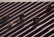 Men in construction gear in Mexico City scaling a row of steel girders on a building.