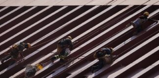 Men in construction gear in Mexico City scaling a row of steel girders on a building.