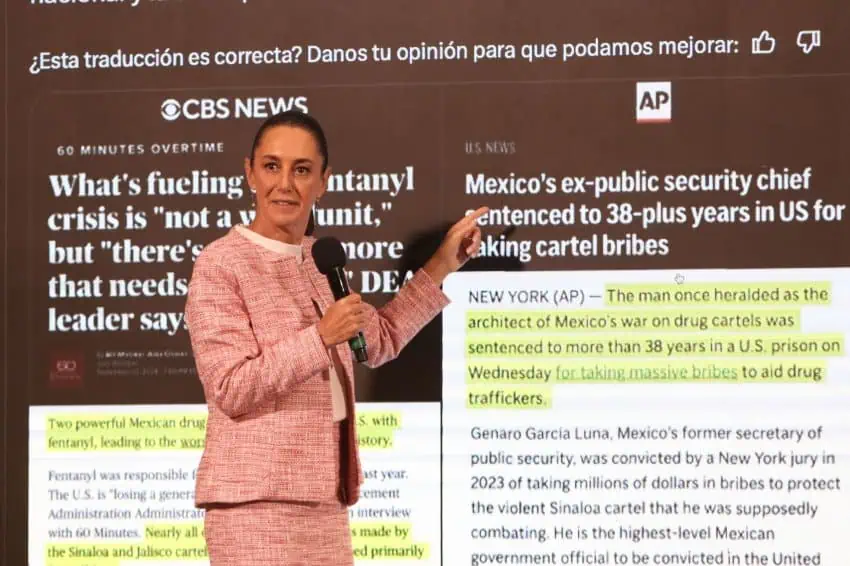 Mexico's President Claudia Sheinbaum standing in front of a projection screen with reprints of articles from CBS News and the Associated Press about Mexico's drug cartels and the fentanyl crisis.