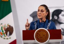 Mexico's President Claudia Sheinbaum at her daily press conference. She is holding up a finger as she makes a point to reporters behind a podium in the National Palace press briefing room