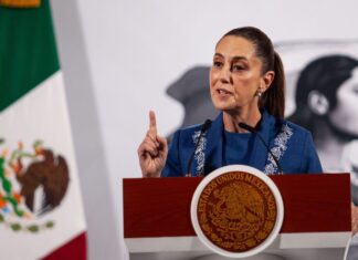 Mexico's President Claudia Sheinbaum at her daily press conference. She is holding up a finger as she makes a point to reporters behind a podium in the National Palace press briefing room