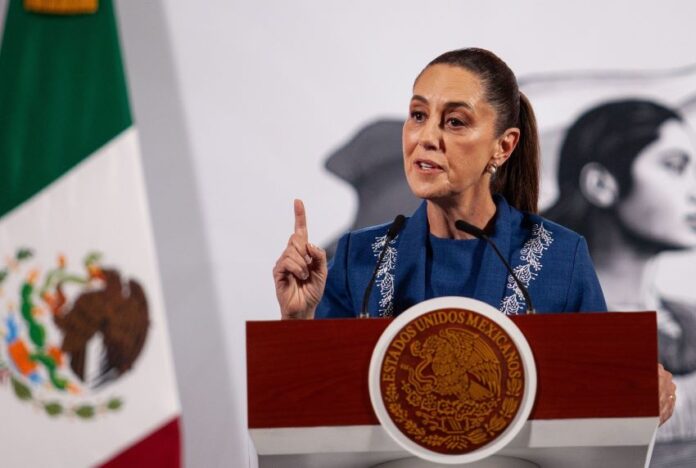 Mexico's President Claudia Sheinbaum at her daily press conference. She is holding up a finger as she makes a point to reporters behind a podium in the National Palace press briefing room