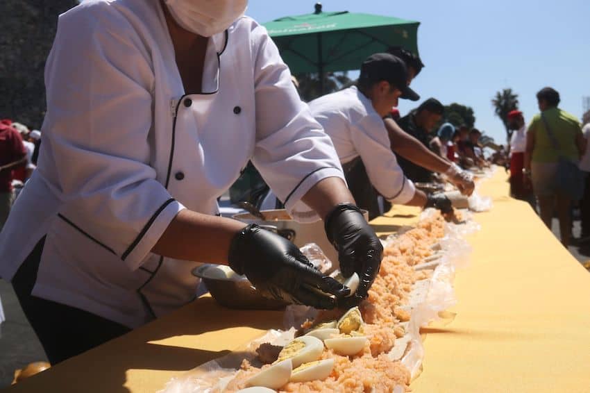 People in white jackets assemble a long taco acorazado in Cuernavaca, Morelos