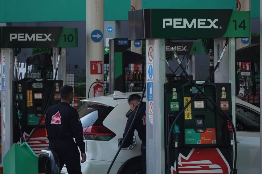 Pemex station attendants in uniform pumping gas into a car's gas tank.