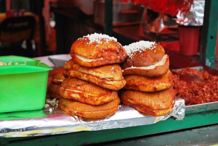 Pambazo sandwiches sit stacked on the edge of a food stall