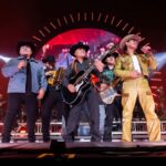 The band Grupo Firme plays together on a stage