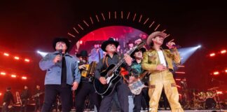 The band Grupo Firme plays together on a stage