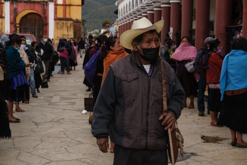 Mexican elderly man with a leather bag done with indigenous flourishes waiting in line in a main plaza in San Cristobal de las Casas, Chiapas.