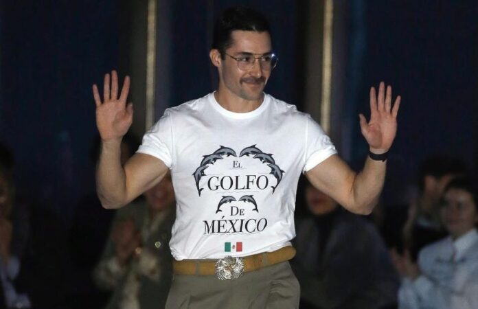 Mexican designer Patrick Campillo on a New York Fashion Week runway wearing a white T-shirt reading 