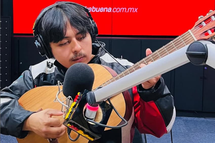 Mexican young man playing an acoustic guitar to a radio microphone on a media show in Mexico