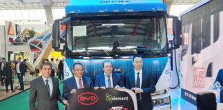 Men in suits stand in front of an electric semi-trailer