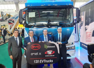 Men in suits stand in front of an electric semi-trailer