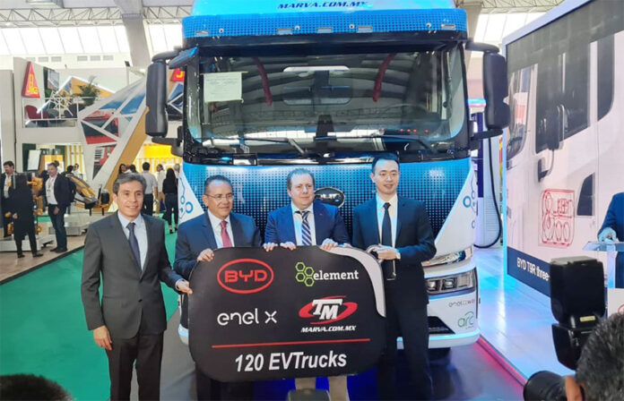 Men in suits stand in front of an electric semi-trailer