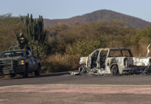 Soldiers guard a burned out car (narco blockade) in rural Sinaloa