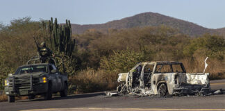 Soldiers guard a burned out car (narco blockade) in rural Sinaloa