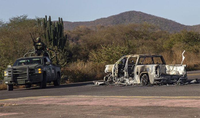 Soldiers guard a burned out car (narco blockade) in rural Sinaloa