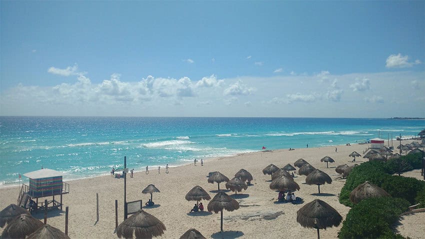 Palapas dot a white sand Caribbean beach in Cancún, voted one of the best in the world