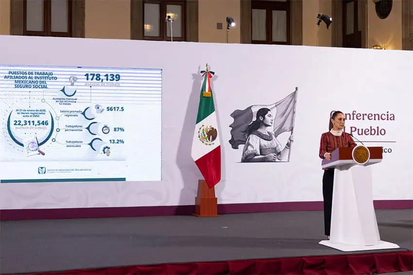 President Claudia Sheinbaum of Mexico stands at a podium in front of a presentation related to the salaries of workers registered with the IMSS