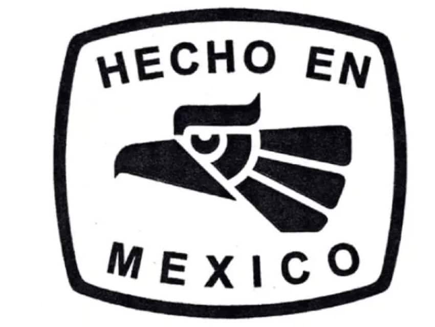 Old black and white logo for Mexico's "Hecho en Mexico" brand. Features a blocky, stylized image of an eagle at the center that recalls Aztec carvings. The logo has a thick black border around it. At the top, it says "Hecho En" and at the bottom, it says "Mexico"