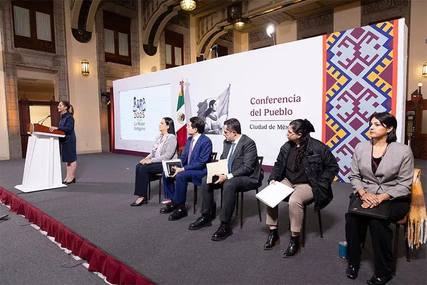 Sheinbaum at a podium next seated speakers waiting their turns at the mañanera morning press conference, talking about the potential impact of tariffs on investment in Mexico