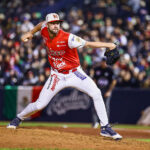 A baseball pitcher in a red Mexican uniform throws the ball at a Caribbean Series Mexico vs Dominican Republic game