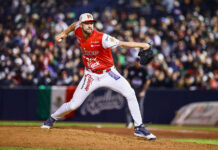 A baseball pitcher in a red Mexican uniform throws the ball at a Caribbean Series Mexico vs Dominican Republic game