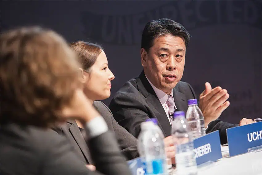 Nissan CEO Makoto Uchida gestures while his sits speaking at a discussion panel