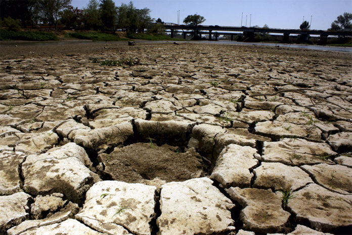 Cracks run through the dirt in a dried-out reservoir, representing intense drought in northwest Mexico